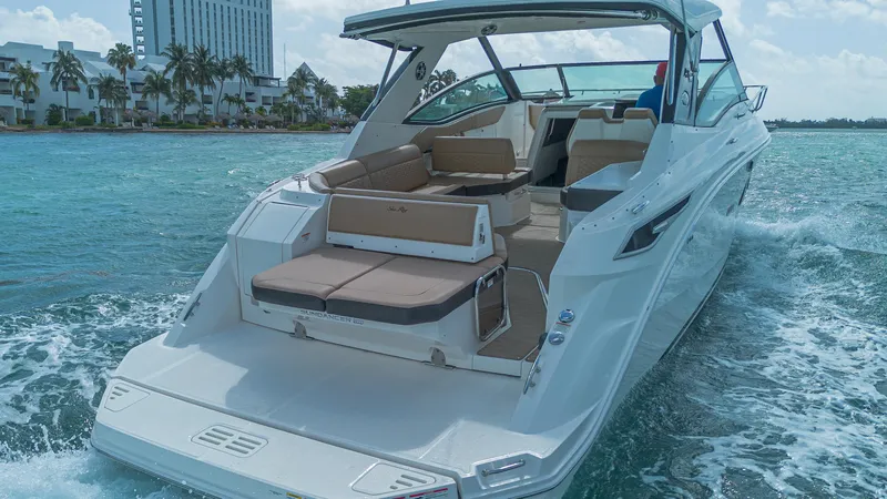 White Kraken Yacht Photos Pics 2023 Sea Ray Sundancer 320 cruising on clear blue water near a coastal city.