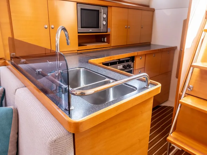  Yacht Photos Pics Modern kitchen interior of 2006 Hanse 370 yacht with sink, microwave, and wooden cabinetry.