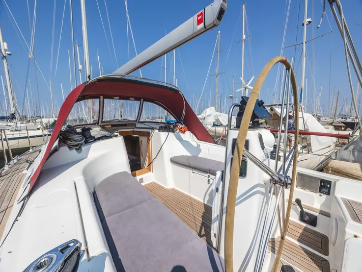  Yacht Photos Pics 2006 Hanse 370 sailboat cockpit with red canopy, wooden wheel, and marina background.