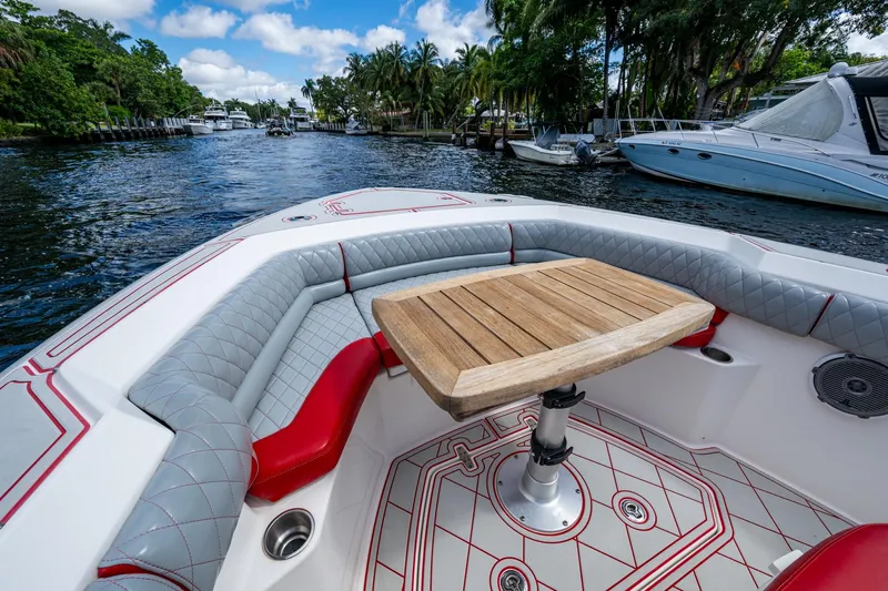 Dare To Dream's Sidechick Yacht Photos Pics 2018 Boston Whaler 330 boat interior with cushioned seating and wooden table on a scenic waterway.