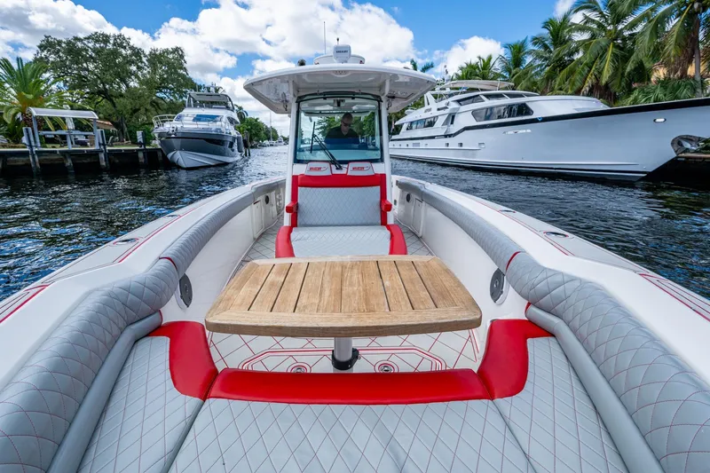 Dare To Dream's Sidechick Yacht Photos Pics 2018 Boston Whaler 330 boat interior with wooden table, docked near luxury yachts.