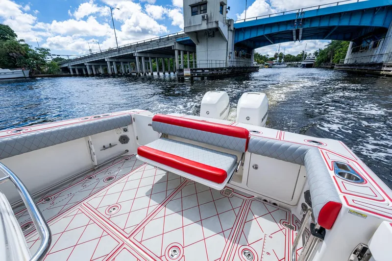 Dare To Dream's Sidechick Yacht Photos Pics 2018 Boston Whaler 330 boat interior with red accents, cruising under a blue bridge.