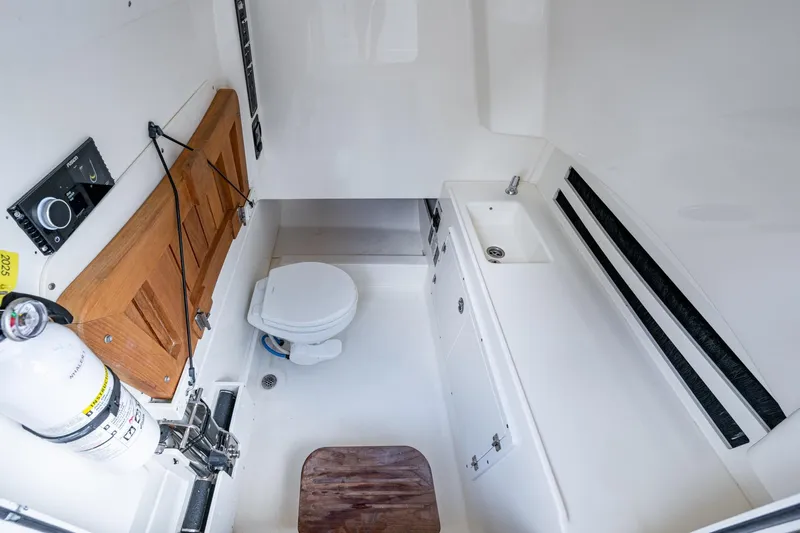 Dare To Dream's Sidechick Yacht Photos Pics 2018 Boston Whaler 330 interior cabin with toilet, sink, and storage.