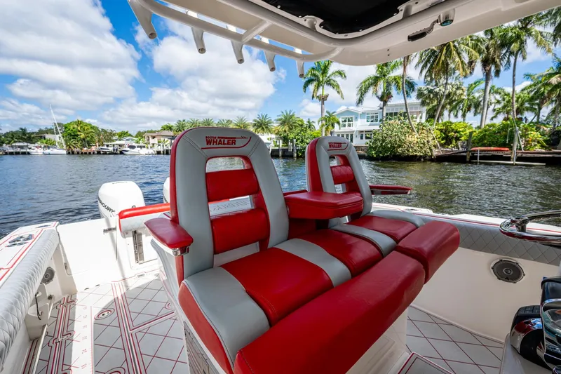 Dare To Dream's Sidechick Yacht Photos Pics 2018 Boston Whaler 330 boat interior with red and gray seating, dockside view.