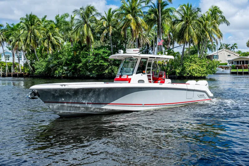 Dare To Dream's Sidechick Yacht Photos Pics 2018 Boston Whaler 330 boat cruising on a tropical waterway with palm trees.