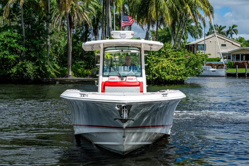 Dare To Dream's Sidechick Yacht Photos Pics 2018 Boston Whaler 330 boat cruising on a scenic waterway with palm trees.