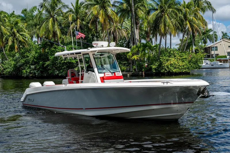 Dare To Dream's Sidechick Yacht Photos Pics 2018 Boston Whaler 330 boat cruising on a tropical waterway with palm trees.