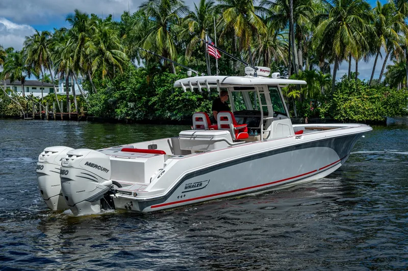 Dare To Dream's Sidechick Yacht Photos Pics 2018 Boston Whaler 330 boat cruising on water, surrounded by lush palm trees.