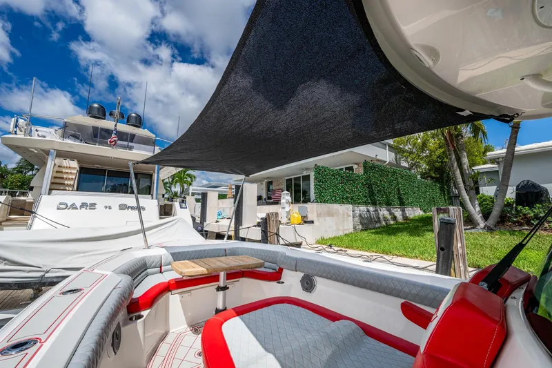 Dare To Dream's Sidechick Yacht Photos Pics 2018 Boston Whaler 330 boat docked, featuring red and gray seating under a sunshade.