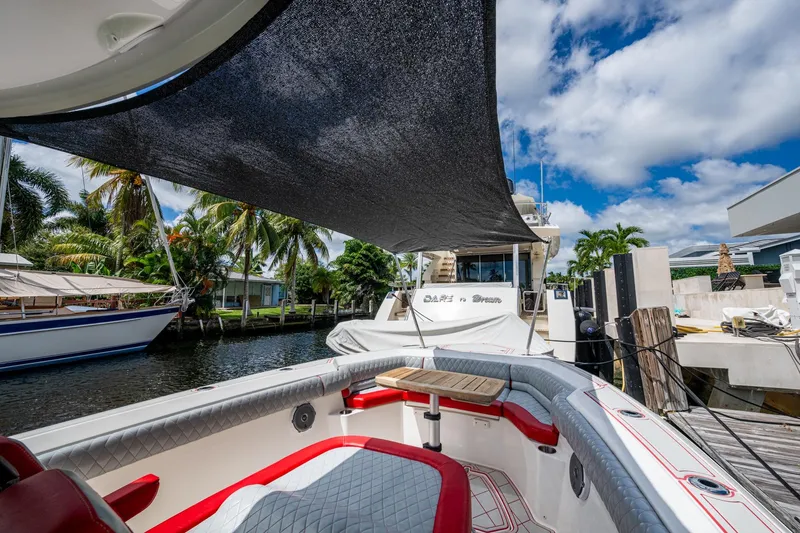 Dare To Dream's Sidechick Yacht Photos Pics 2018 Boston Whaler 330 boat docked, featuring shaded seating area and tropical surroundings.
