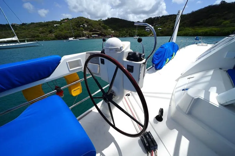  Yacht Photos Pics Steering wheel of 2003 Catana 522 Ocean Class yacht with blue seating, docked in scenic bay.