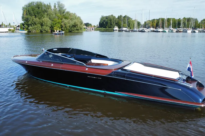  Yacht Photos Pics 2025 Riva Aquariva Special luxury boat on calm water, surrounded by trees and marina.