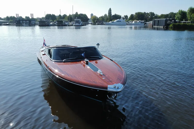  Yacht Photos Pics 2025 Riva Aquariva Special luxury boat on calm water, surrounded by marina scenery.
