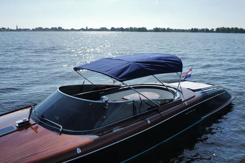  Yacht Photos Pics 2025 Riva Aquariva Special boat with blue canopy on a sunny lake.