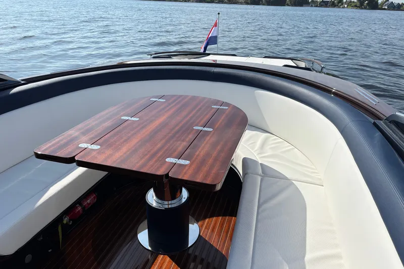  Yacht Photos Pics 2025 Riva Aquariva Special boat interior with wooden table and white seating on a lake.