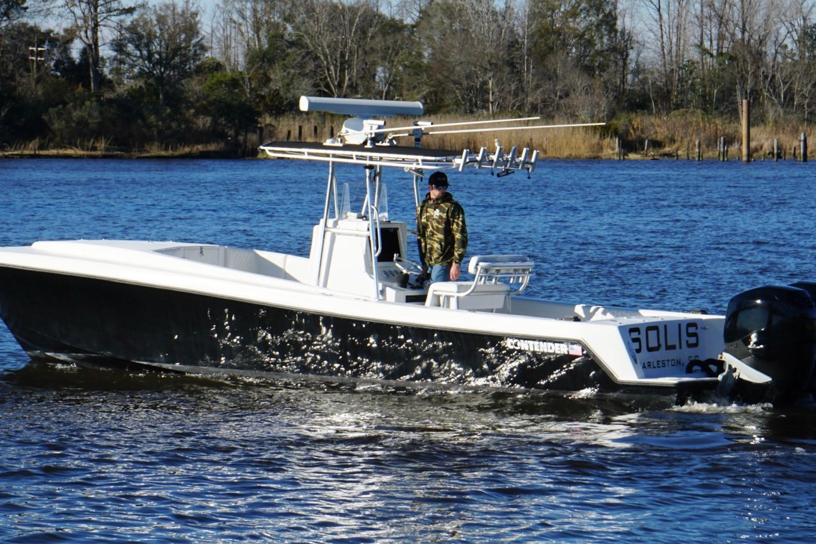 2005 Contender 31 Cuddy boat cruising on a calm river with a person onboard.
