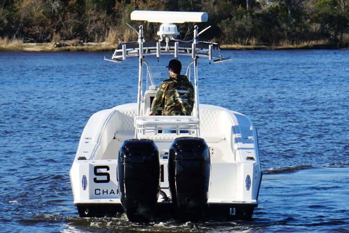 2005 Contender 31 Cuddy boat on water, rear view with dual engines.