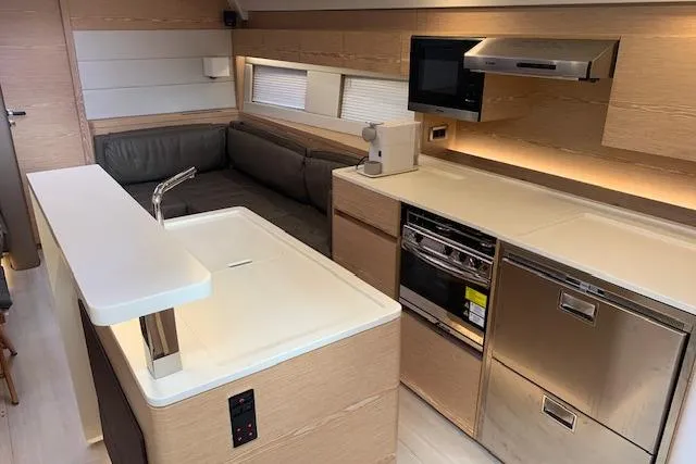  Yacht Photos Pics Modern kitchen interior of 2017 Hanse 588 yacht with sleek appliances and cozy seating area.