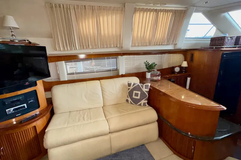  Yacht Photos Pics 2003 Carver 396 Motor Yacht interior with beige sofa, TV, and wooden cabinetry.
