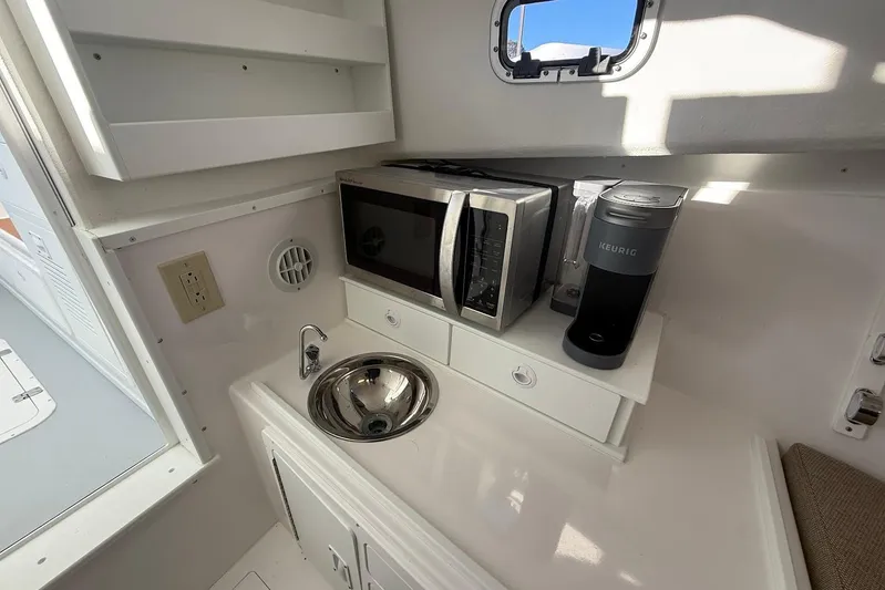 Daybreak Yacht Photos Pics Compact kitchenette in 2023 Steiger Craft 31 Chesapeake boat with microwave, sink, and coffee maker.
