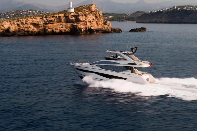 Travitude Yacht Photos Pics Luxury Pearl 62 yacht cruising near rocky coastline with lighthouse, 2020 model.