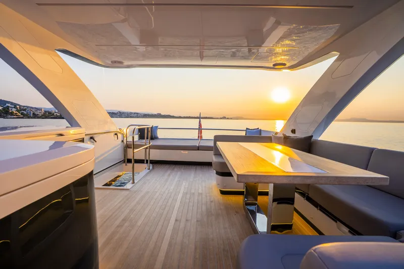Travitude Yacht Photos Pics Luxurious Pearl 62 yacht interior with sunset view, featuring elegant seating and a sleek table, 2020 model.