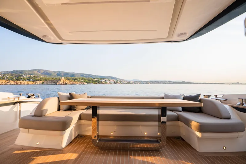 Travitude Yacht Photos Pics Luxurious Pearl 62 yacht deck with elegant seating, overlooking serene coastal waters.