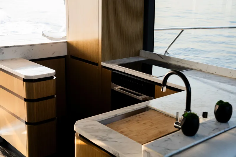 Travitude Yacht Photos Pics Luxurious yacht kitchen interior with marble countertops, modern appliances, and ocean view. Pearl 62, 2020.