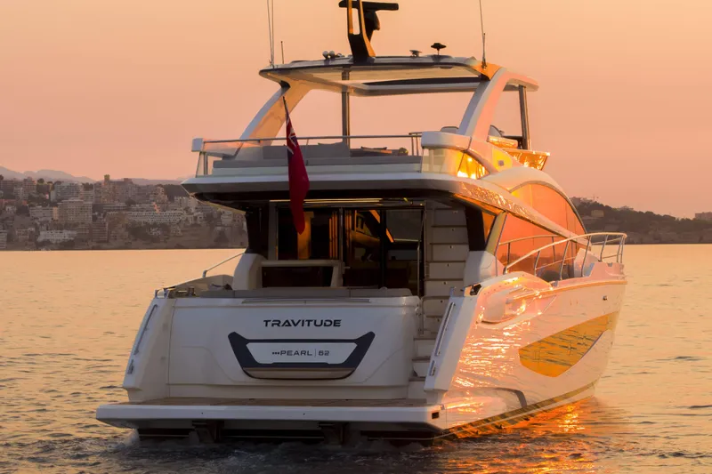 Travitude Yacht Photos Pics Luxurious 2020 Pearl 62 yacht at sunset, reflecting golden hues on calm waters.