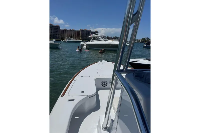  Yacht Photos Pics 2024 Billfish 24 boat on water with people swimming nearby, buildings in background.