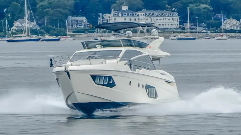 Low Key Yacht Photos Pics 2019 Absolute 50 Fly yacht cruising on water with scenic coastal background.