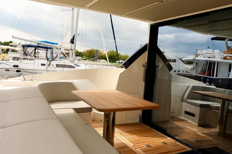 Low Key Yacht Photos Pics Luxurious 2019 Absolute 50 Fly yacht with elegant seating and wooden table on deck.