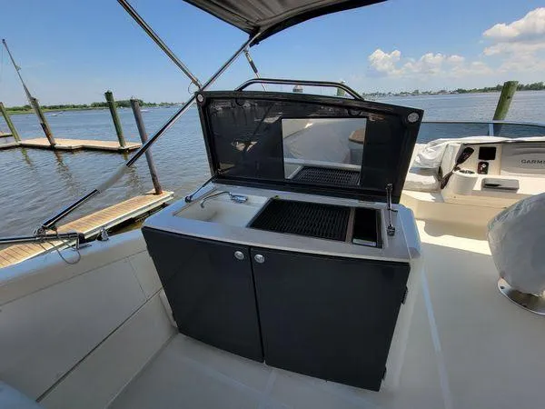 Low Key Yacht Photos Pics Outdoor kitchen on 2019 Absolute 50 Fly yacht with grill and sink, docked by the water.