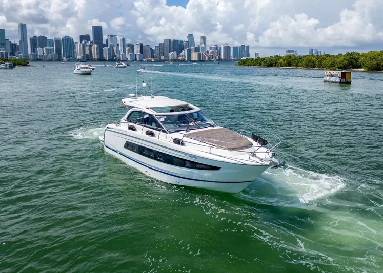  Yacht Photos Pics 2019 Jeanneau Leader 40 yacht cruising near city skyline and lush greenery.