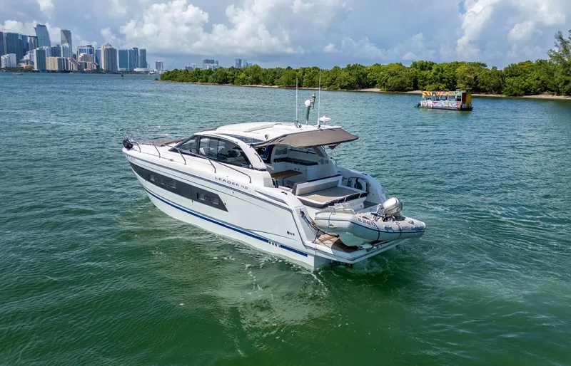  Yacht Photos Pics 2019 Jeanneau Leader 40 yacht cruising near a city skyline and lush greenery.