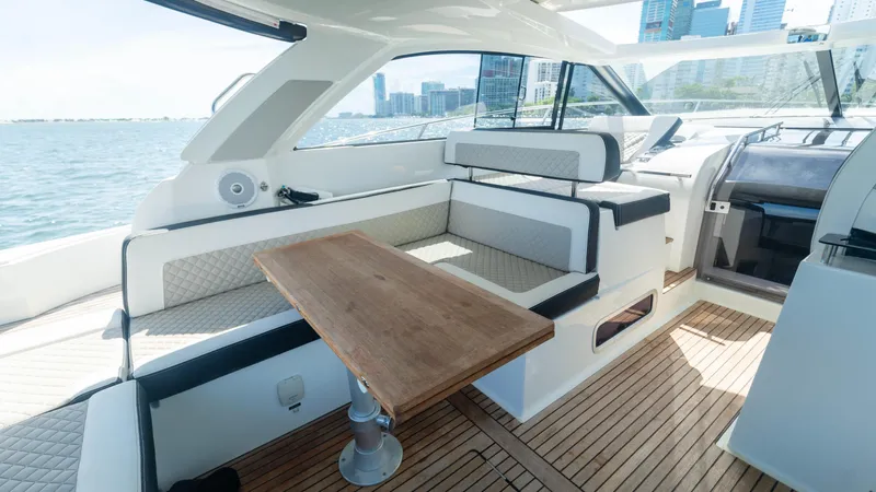  Yacht Photos Pics 2019 Jeanneau Leader 40 yacht interior with seating and wooden table, overlooking city skyline.