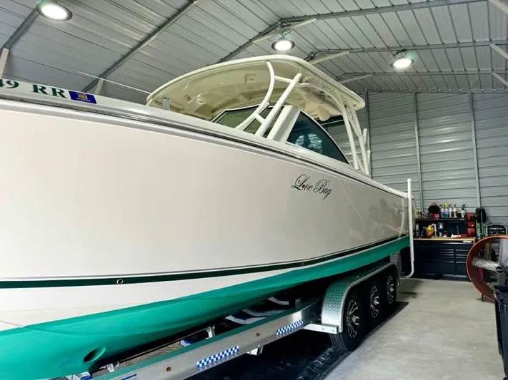  Yacht Photos Pics 2018 Sailfish 325 DC boat in a garage, on a trailer, with green accents.