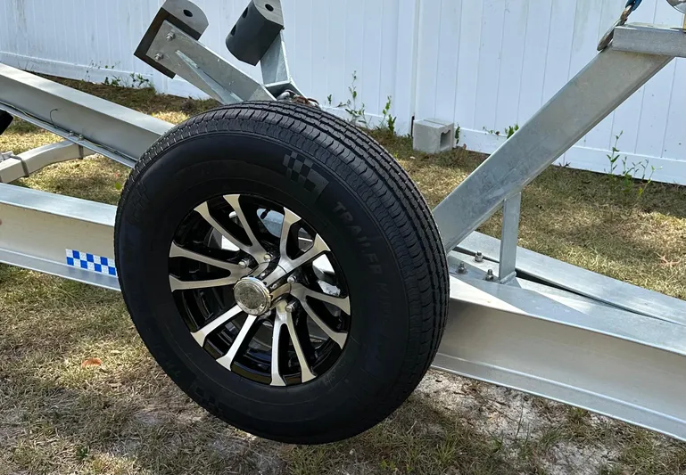  Yacht Photos Pics Trailer wheel on grass, part of a 2018 Sailfish 325 DC boat trailer.
