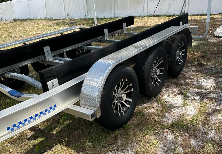  Yacht Photos Pics Triple-axle boat trailer for 2018 Sailfish 325 DC, parked on grass.