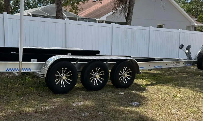  Yacht Photos Pics Triple-axle boat trailer parked on grass, near a white fence, suitable for Sailfish 325 DC.