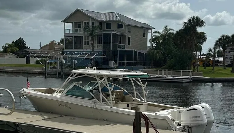  Yacht Photos Pics 2018 Sailfish 325 DC boat docked near a waterfront house with palm trees.