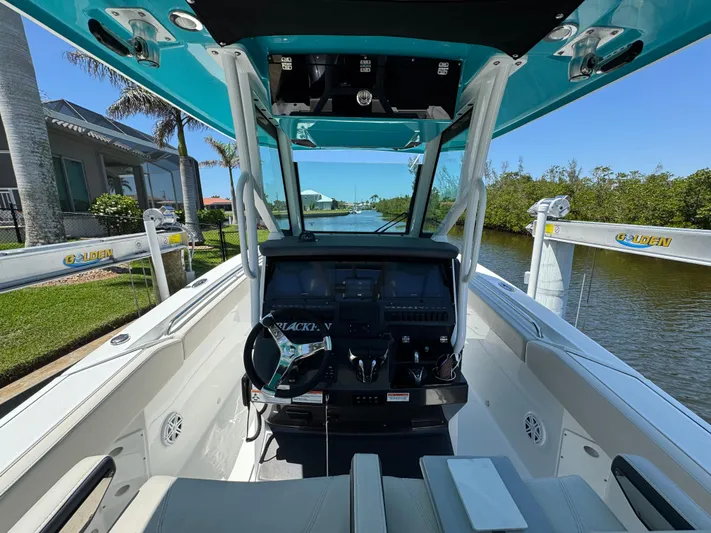  Yacht Photos Pics 2021 Blackfin 272 CC boat cockpit with modern controls, docked by a scenic waterway.