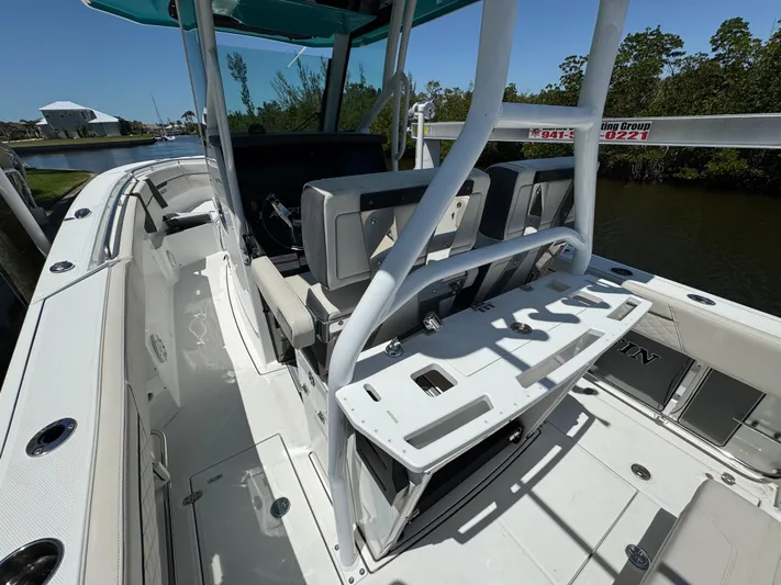  Yacht Photos Pics 2021 Blackfin 272 CC boat interior with seating and fishing rod holders, docked near water.