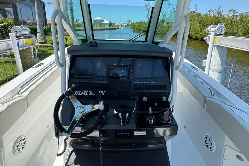  Yacht Photos Pics 2021 Blackfin 272 CC boat cockpit with steering wheel and control panel, docked by a canal.