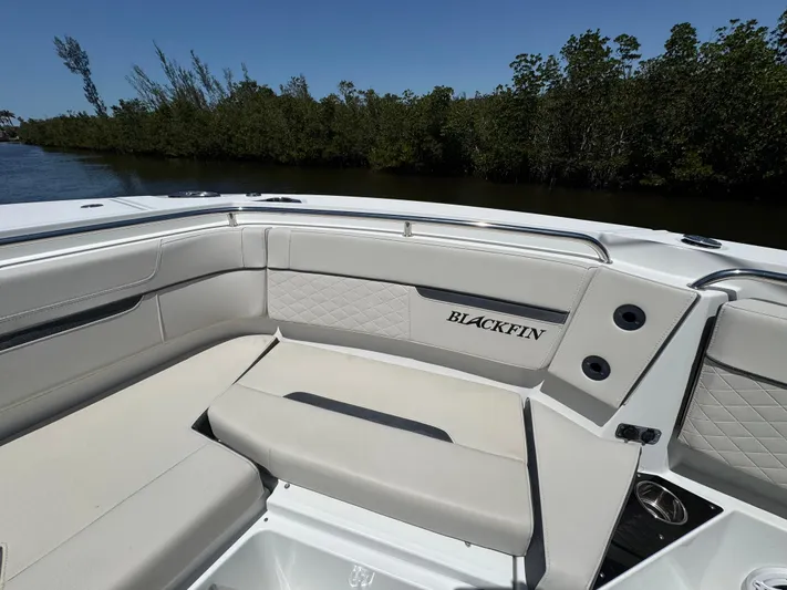  Yacht Photos Pics 2021 Blackfin 272 CC boat interior with cushioned seating, near lush greenery.