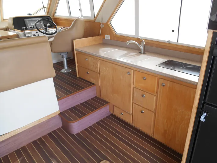Lucky Yacht Photos Pics Interior of 2001 Californian 39 boat with kitchen and helm, featuring wood cabinetry and flooring.