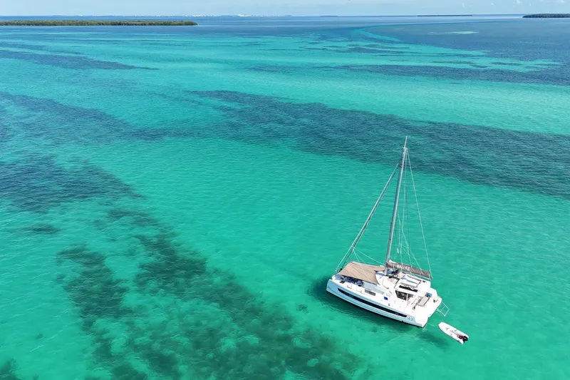 Tamboo Yacht Photos Pics Sailboat Bali 4.2 (2023) on turquoise sea, near lush island.