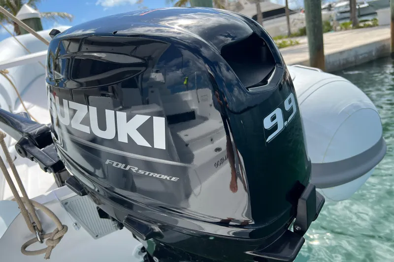 Tamboo Yacht Photos Pics Suzuki 9.9 four-stroke outboard motor on 2023 Bali 4.2 boat, docked by water.