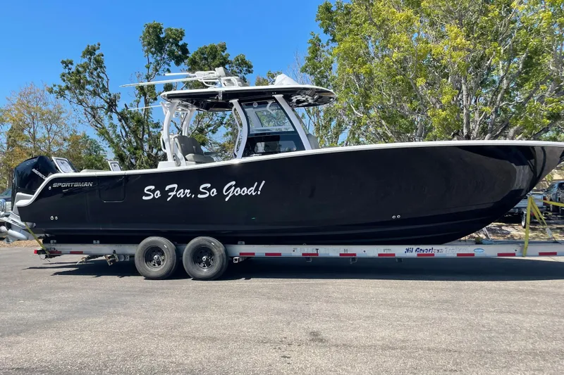  Yacht Photos Pics 2023 Sportsman Open 322 Center Console boat on trailer, black with "So Far, So Good!" text.
