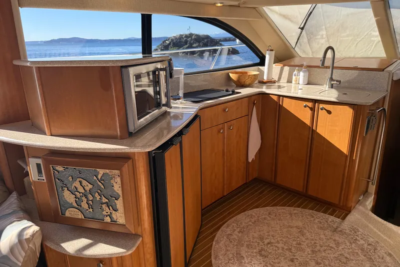  Yacht Photos Pics Luxurious 2004 Meridian 411 Sedan yacht kitchen with ocean view, featuring wood cabinetry and modern appliances.